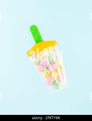 Popsicle ice cream filled with colorful Easter eggs on pastel blue background. Easter minimal concept. Creative Happy Easter or spring layout. Stock Photo