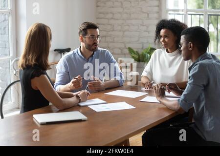 Skilled mixed race colleagues discussing project indoors. Stock Photo