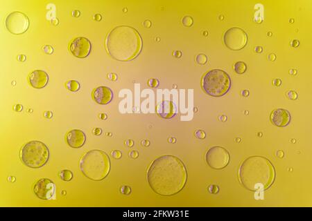 Bubbles of gel and serum with purple shadows and highlights. On a yellow background, top view. Stock Photo