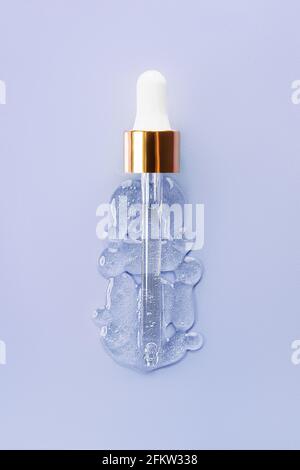 Liquid serum and dropper on a blue background top view. Serum drops in the form of a bottle with a pipette. Stock Photo