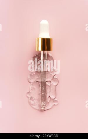 Liquid serum and dropper on a pink background top view. Serum drops in the form of a bottle with a pipette. Stock Photo