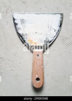 Putty knife stained with putty - laying on cement floor Stock Photo