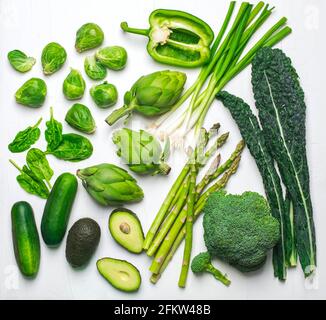 Green vegetables and herbs assortment on a white background. Flat lay series of assorted green vegetables. Fresh organic produce. Healthy food. Top vi Stock Photo