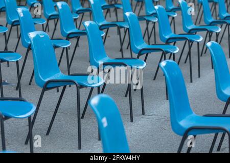 Rows and columns of nondescript blue plastic chairs, consecutive, arranged in a line, at similar intervals of space, facing the same place. Retiro Par Stock Photo