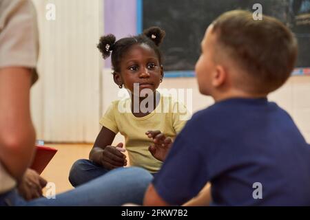 Two children in international kindergarten are playing on the floor together Stock Photo