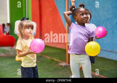Group of multicultural children playing ball together in daycare gym class Stock Photo