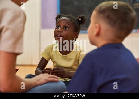 African girl talks to daycare worker or childminder in international kindergarten Stock Photo