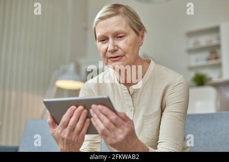 Senior woman using digital tablet at home. The use of technology by the elderly. Stock Photo