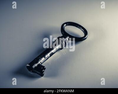 Grayscale photo of golden key isolated on white background. Old rusty door key. Antique gold key. Metal silver key. Selective focus. Stock Photo