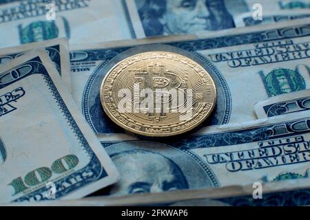 Bitcoin cryptocurrency coin lies on one hundred dollar bills Stock Photo