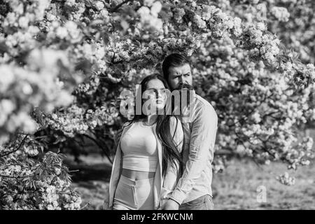 Spring pink sakura blossom. man and woman standing under sakura tree. lovers enjoying view of cherry blossom. flourishing flowers on branch. romantic Stock Photo