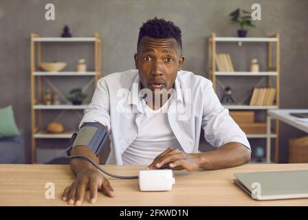 Young African American man with hypertension shocked after measuring his blood pressure Stock Photo