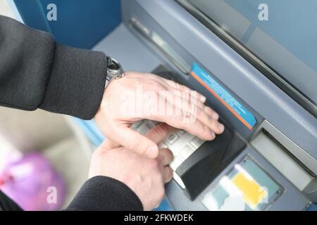 Man enters code on ATM keyboard and closes it with his hand Stock Photo