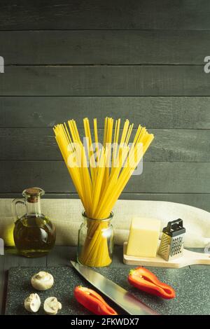 Raw dry Italian spaghetti and fresh vegetables. Spaghetti pasta, vegetables and spices and cheese on a wooden table. Background with space for text