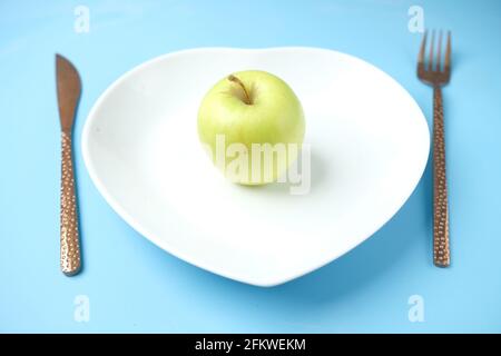 cutlery and empty plate with green apple on blue background  Stock Photo
