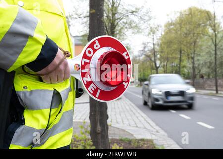 Dresden, Germany. 04th May, 2021. A police officer is standing on a road in front of a car with a waving trowel at a press event to launch the 'Respect through consideration' campaign. The distance to the side of vehicles when overtaking cyclists is being checked. Credit: Sebastian Kahnert/dpa-Zentralbild/dpa/Alamy Live News Stock Photo