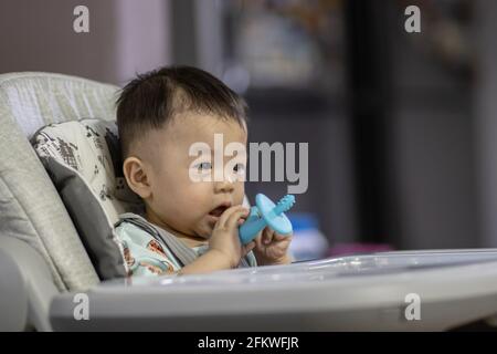 Potrait image of adorble and cute happy Asian Chinese baby boy sit on baby chair playing toy Stock Photo