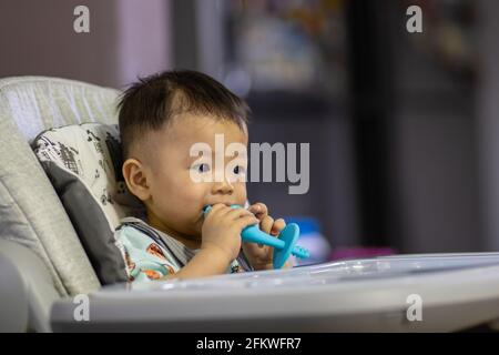 Potrait image of adorble and cute happy Asian Chinese baby boy sit on baby chair playing toy Stock Photo