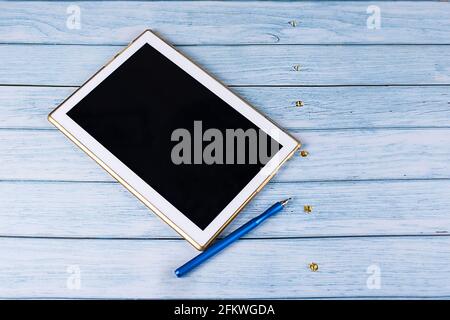 Tablet PC with black screen, near a cup of coffee on a wooden background, hand with a stylus, work process. Concept - Business, Online education Stock Photo