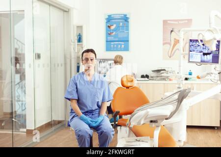 Stomatological nurse looking into camera while waiting for senior doctor to examining tooth radiography sitting in stomatology clinic office. Medical team checking dental consultation Stock Photo