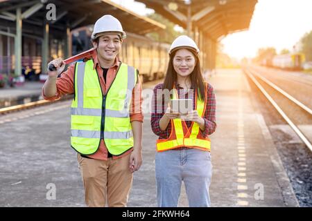 Engineer technician wearing a helmet and safety vest is using a wrench to repair the train with using tablet Stock Photo