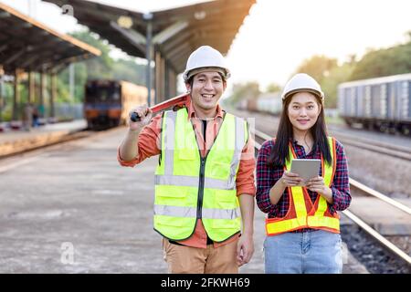 Engineer technician wearing a helmet and safety vest is using a wrench to repair the train with using tablet Stock Photo