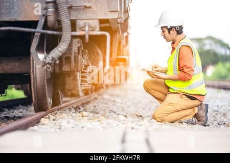Engineer man sitting on railway inspection. construction worker on railways. Engineer work using tablet to report of Train. Stock Photo