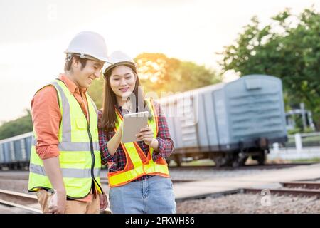 Engineer technician wearing a helmet and safety vest is using a wrench to repair the train with using tablet Stock Photo