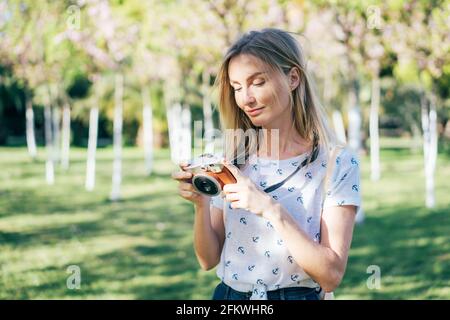 Charming young blonde looks at the camera settings. Woman photographer travels on a warm summer day. Summer weekend travel. Young happy healthy woman Stock Photo