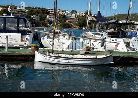 an old traditional fishing boat moored in front of modern sailing yachts in mahon harbour menorca Stock Photo