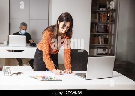 Young businesswoman standing in her home office writing notes - business concept Stock Photo
