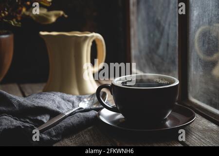 Cup of hot coffee on a rustic wooden table by a window Stock Photo