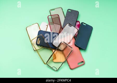 Pile of multicolored plastic back covers for mobile phones on green background Stock Photo