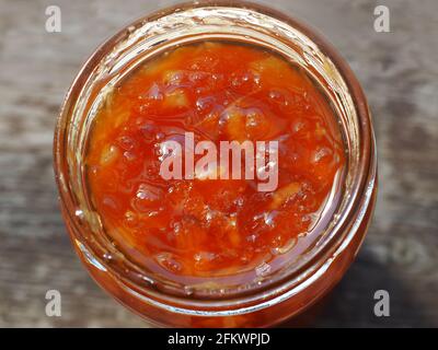 Tangerine lemon jam in a glass jar. Close-up jam on a blurred background. Stock Photo