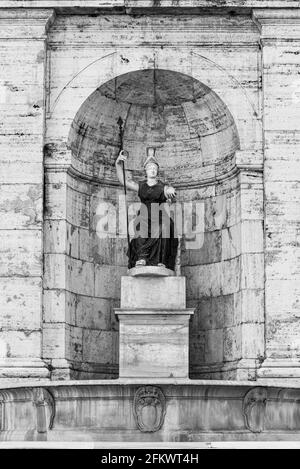 Black and white photo of ancient statue in marble decorating the entrance of an old building in Rome Stock Photo