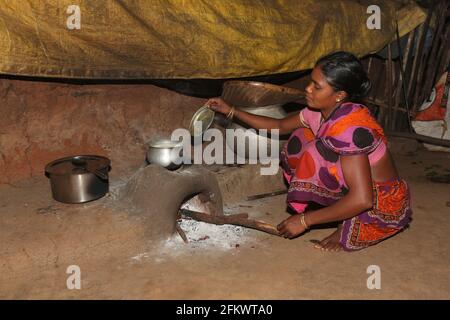 Woman cooking food using traditional mud hearth. DESIA KONDHA TRIBE. Goipeta Village, Odisha, India Stock Photo