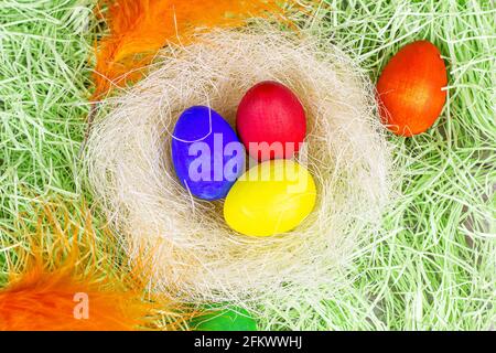 Top view colorful painted Easter eggs decorations in the nest on light green background. Stock Photo