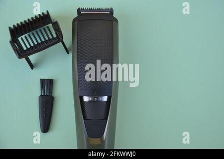 High angle shot of beard trimmer with comb and brush with negative space, Hair trimmer isolated on green background. Stock Photo