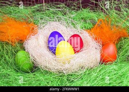 Colorful painted Easter eggs decorations in the nest on light green background. Stock Photo