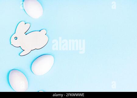 Top view flat lay funny wooden Easter Bunny with eggs as symbols of a holiday with copy space on light pink background. Stock Photo