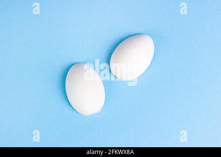Two white wooden eggs on bright light blue background. Stock Photo