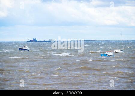 Small Boats at Anchor Ride the Waves During Unseasonal Gales on Thames Estuary in Early May with Southend Pier in Background Stock Photo