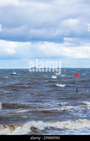 Small Boats at Anchor Ride the Waves During Unseasonal Gales on Thames Estuary in Early May with Southend Pier in Background Stock Photo