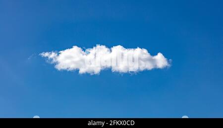 Cloud white on blue sky. One single fluffy cloud isolated on clear sky background, sunny spring day. Stock Photo