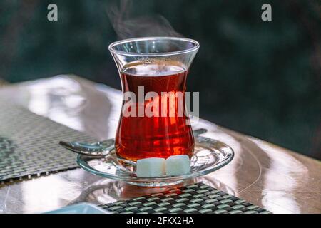 Closeup of traditional Turkish glass cup, bardak, of Turkish black tea with sugar and spoon Stock Photo
