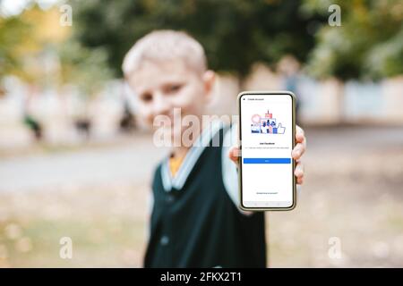 Podolsk, Ukraine - March 29, 2021: Boy hand holds new smartphone with Facebook profile account page on the screen. Social media are using for informat Stock Photo