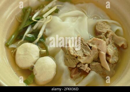 large rice noodles topping slice braised and fermenting with meatball in herb brown soup on bowl Stock Photo