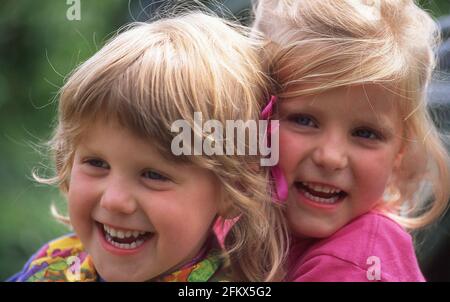 Young sisters hugging and laughing, Berkshire, England, United Kingdom Stock Photo