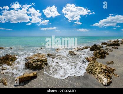 Small waves breaking amoung rocks on the shore of the Gilf of Mexico at Caspersen Beach with blue sky and white clouds in Venice Florida USA Stock Photo