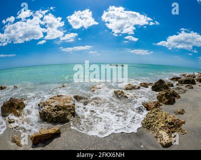 Small waves breaking amoung rocks on the shore of the Gilf of Mexico at Caspersen Beach with blue sky and white clouds in Venice Florida USA Stock Photo